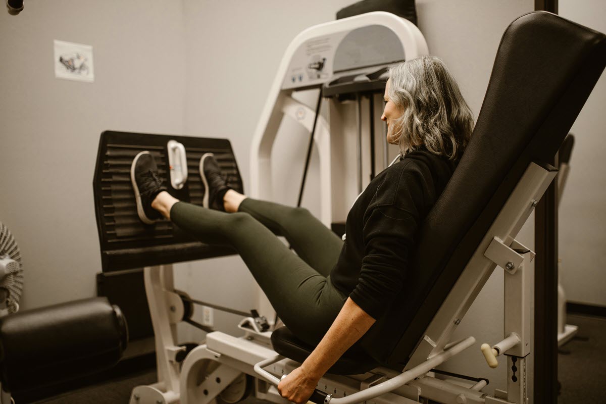 Woman using a leg press machine at the gym as part of a Medicare Advantage fitness benefit